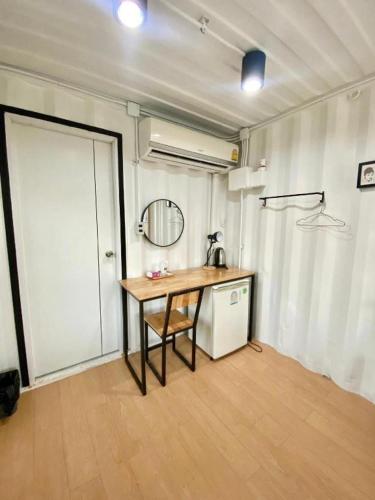 a room with a table and a refrigerator and a door at Boxotel in Maha Sarakham
