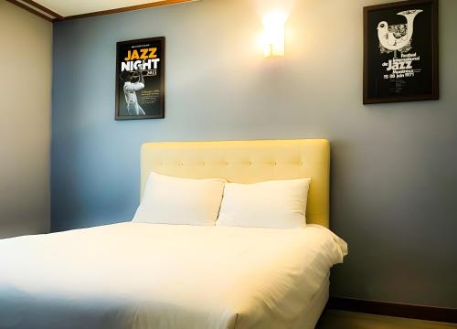 a bedroom with a white bed with two pictures on the wall at Jeju EQ Stay in Jeju