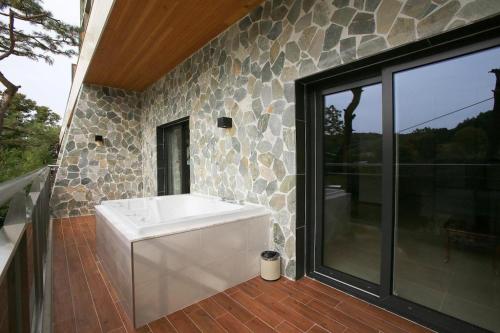 a bath tub in a bathroom with a stone wall at hotel gallery in Pocheon