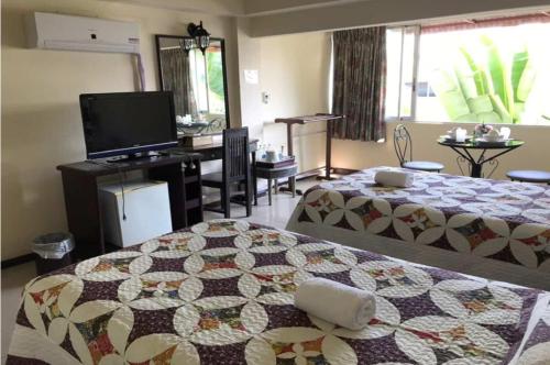 a hotel room with two beds and a television at OYO 903 Madame Kim Hostel in Lampang