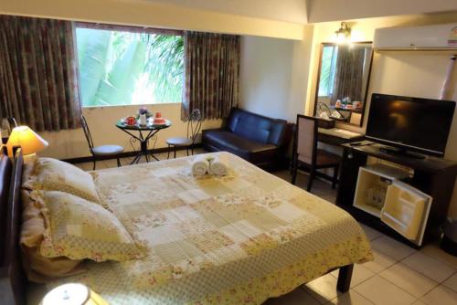 a bedroom with a bed and a television and a chair at OYO 903 Madame Kim Hostel in Lampang