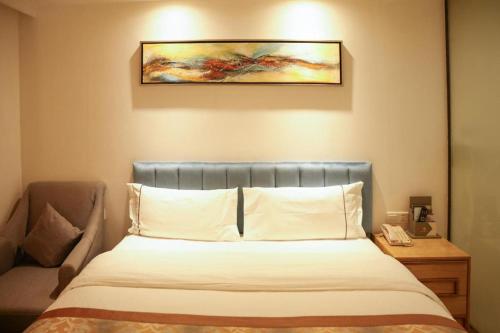 a bedroom with a bed and a painting on the wall at Golden Central Hotel Shenzhen in Shenzhen