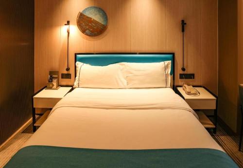 a bedroom with a large white bed with two tables at Golden Central Hotel Shenzhen in Shenzhen