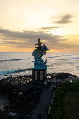 a statue in front of the ocean at sunset at Amar Boutique Hotel in Canggu