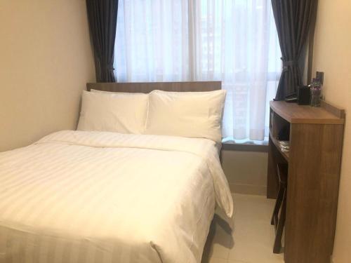 um quarto com uma cama branca com janela em WE Hotel Kowloon em Hong Kong