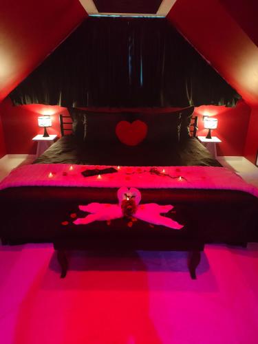 - une chambre dotée d'un lit rose avec un cœur dans l'établissement LE QUART D'HEURE AMERICAIN, à Bailleul