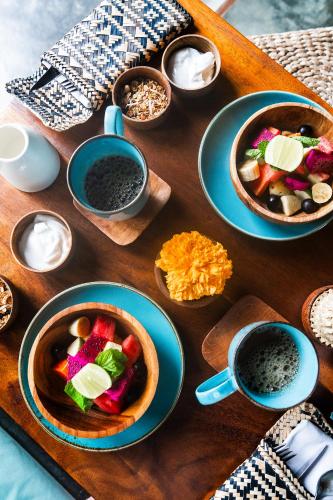 a wooden table with plates of food and bowls of dips at Amar Boutique Hotel in Canggu