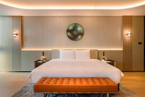 a bedroom with a large bed with a orange bench at Jeju Bolton Hotel in Jeju