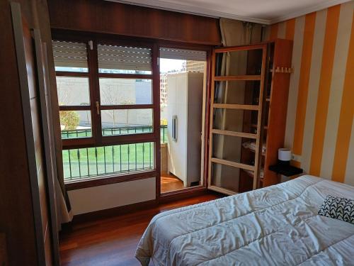 a bedroom with a bed and a large window at Apartamento completo a 7 minutos de la playa con parking in Castro-Urdiales