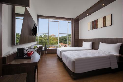 a hotel room with two beds and a desk at Neo Dipatiukur Bandung by ASTON in Bandung