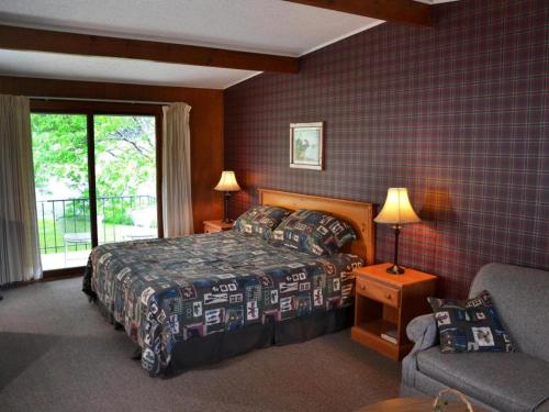 a bedroom with a bed and a chair and a window at Birchwood Inn in Harbor Springs