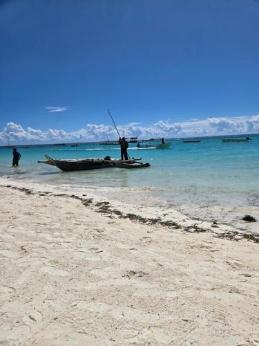 a man standing on a boat on the beach at Smile Boutique Beach hotel in Nungwi