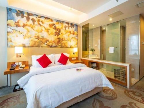a bedroom with a large bed with a painting on the wall at Jinjiang Metropolo Hotel - Taizhou Wanda Plaza in Taizhou