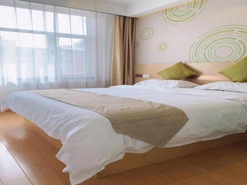 a large bed in a bedroom with a large window at GreenTree Inn Langfang GuAn County Xinyuan Street Express Hotel in Langfang