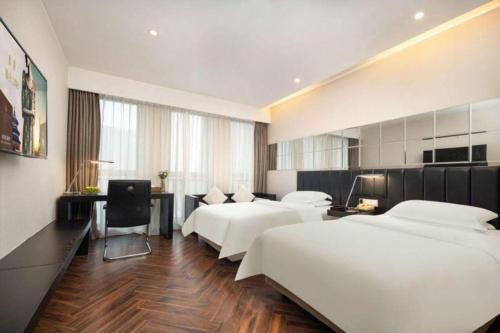a hotel room with two beds and a desk at Jinjiang Metropolo Hotel - Taizhou Wanda Plaza in Taizhou