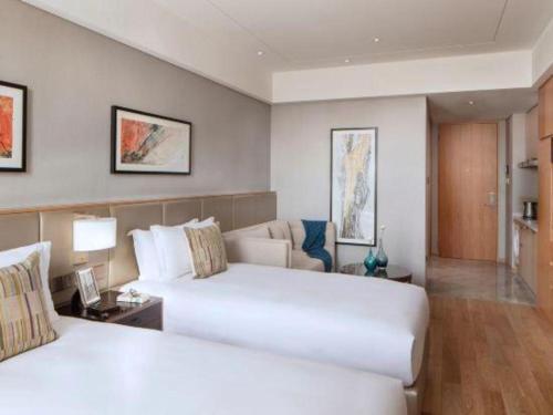 a hotel room with two beds and a couch at Shama Daqing Heilongjiang in Daqing