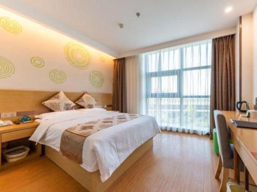 a bedroom with a bed and a desk and a window at GreenTree Inn Nantong University Industrial Expo City Express Hotel in Nantong