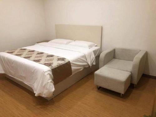 a bedroom with a large bed with a chair and a foot stool at GreenTree Inn Nantong University Industrial Expo City Express Hotel in Nantong