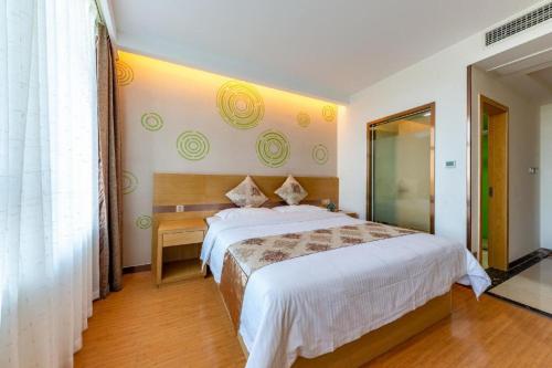 a bedroom with a large bed and a wooden floor at GreenTree Inn Nantong University Industrial Expo City Express Hotel in Nantong