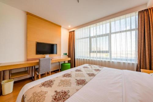 a hotel room with a bed and a desk and a television at GreenTree Inn Nantong University Industrial Expo City Express Hotel in Nantong