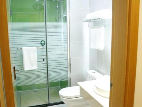 a bathroom with a toilet and a glass shower at GreenTree Inn Ordos Kangbashi District Ulan Mulun Street Branch in Ordos