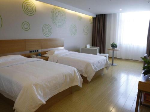 a hotel room with two beds and a window at GreenTree Inn Ordos Kangbashi District Ulan Mulun Street Branch in Ordos