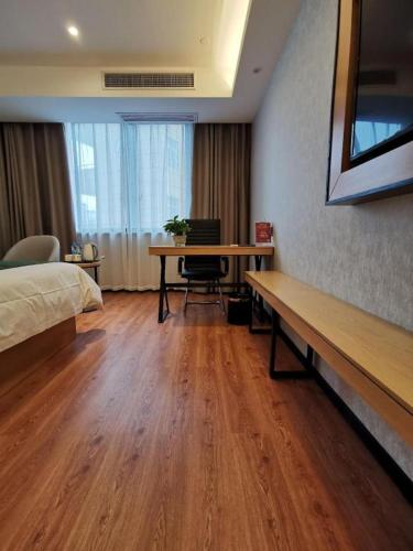 a bedroom with a desk and a bed and a table at GreenTree Inn Ganzhou Gan County Bus Station in Ganzhou