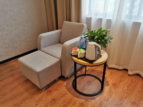 a living room with a chair and a table with a tv at GreenTree Inn Ganzhou Gan County Bus Station in Ganzhou