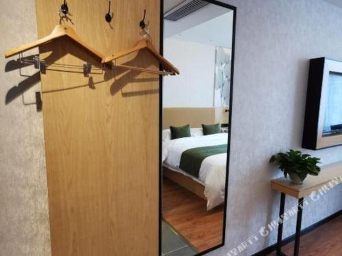 a mirror in a room with a bed and a bedroom at GreenTree Inn Ganzhou Gan County Bus Station in Ganzhou