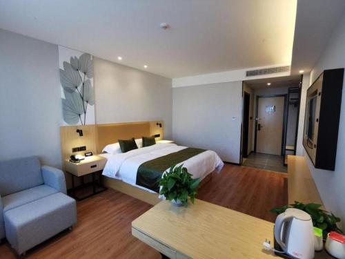 a bedroom with a bed and a couch and a tv at GreenTree Inn Ganzhou Gan County Bus Station in Ganzhou