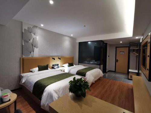 a hotel room with two beds and a television at GreenTree Inn Ganzhou Gan County Bus Station in Ganzhou