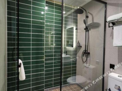 a green tiled bathroom with a glass shower at GreenTree Inn Ganzhou Gan County Bus Station in Ganzhou