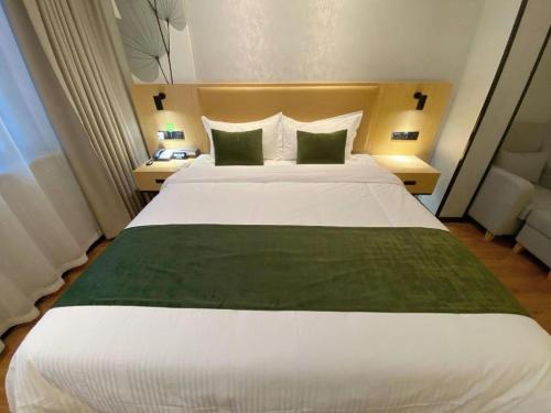 a bedroom with a large white bed with two green pillows at GreenTree Inn Ganzhou Gan County Bus Station in Ganzhou