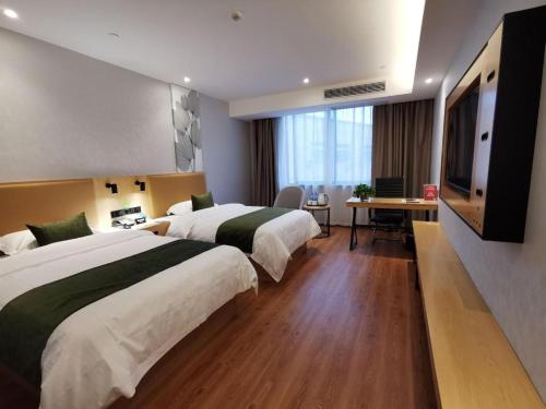 a hotel room with two beds and a flat screen tv at GreenTree Inn Ganzhou Gan County Bus Station in Ganzhou