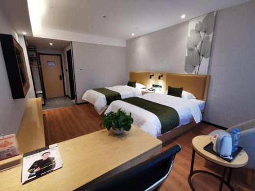 a hotel room with two beds and a table at GreenTree Inn Ganzhou Gan County Bus Station in Ganzhou