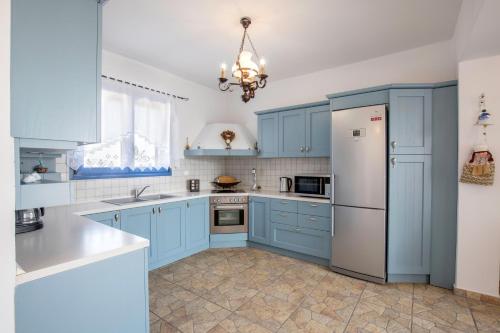 a kitchen with blue cabinets and a refrigerator at Villa Elias in Archangelos