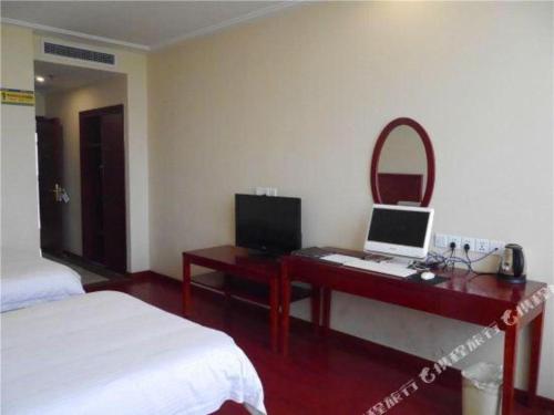 a bedroom with a desk with a laptop and a mirror at GreenTree Inn Tianjin Wuqing Distric Bohai Market in Tianjin