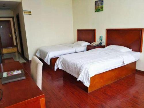 a bedroom with two beds and a wooden floor at GreenTree Inn Tianjin Wuqing Distric Bohai Market in Tianjin