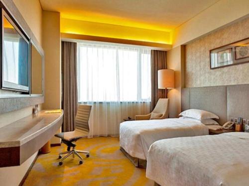 a hotel room with two beds and a desk at Wuhan Gleetour Hotel in Wuhan