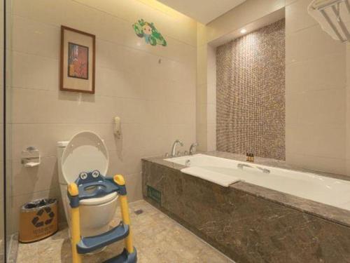 a bathroom with a toilet and a bath tub with a toy at Wuhan Gleetour Hotel in Wuhan