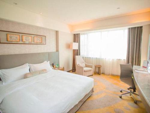 a hotel room with a large white bed and a desk at Wuhan Gleetour Hotel in Wuhan