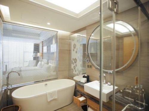 a bathroom with a tub and a sink and a mirror at Zhangjiagang Zhonglian GDH International Hotel in Zhangjiagang