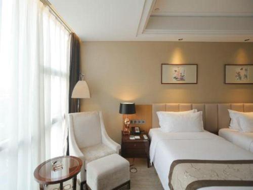 a hotel room with a bed and a chair at Zhangjiagang Zhonglian GDH International Hotel in Zhangjiagang