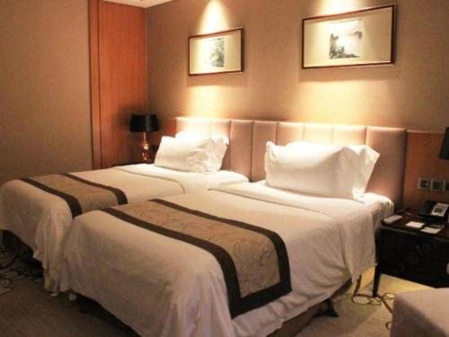 a hotel room with two beds with white pillows at Zhangjiagang Zhonglian GDH International Hotel in Zhangjiagang