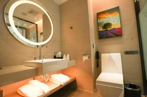 a bathroom with a sink and a mirror and a toilet at Lavande Hotel Wuhan Huanghelou Branch in Wuhan