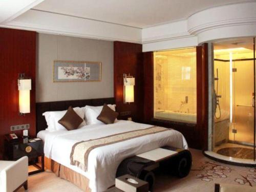 a bedroom with a large bed and a shower at Zhangjiagang Zhonglian GDH International Hotel in Zhangjiagang