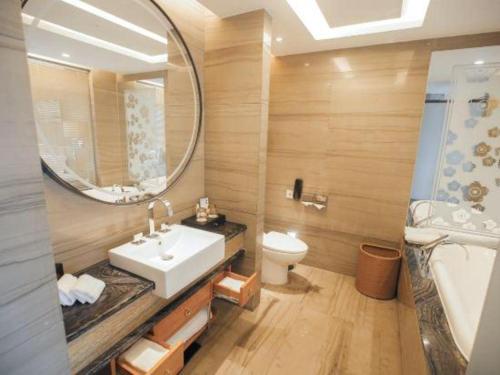 a bathroom with a sink and a toilet and a mirror at Zhangjiagang Zhonglian GDH International Hotel in Zhangjiagang