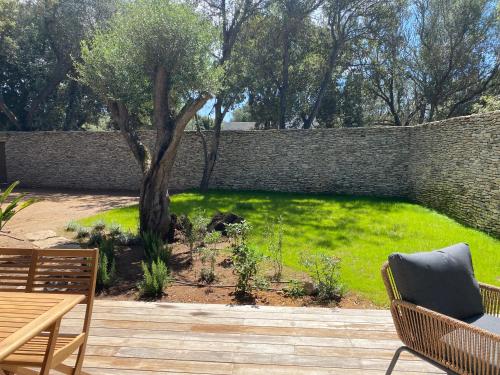 un jardin avec un arbre et un mur en briques dans l'établissement Perla Bianca, à Bonifacio