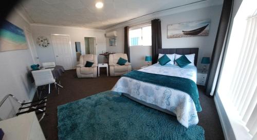a bedroom with a bed and a room with chairs at Palm Beach Guest House in Rockingham