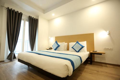 a hotel room with a large bed with blue pillows at Hotel Grand Arcasia in Ghaziabad